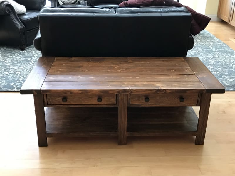 A dark-stained coffee table with two drawers and a lower shelf in a living room