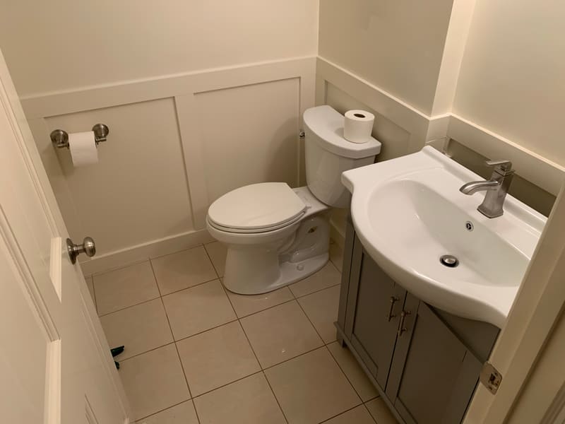 A powder room with new wainscoting and a vanity installed, ready for wallpaper