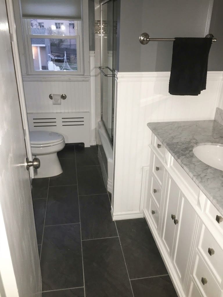 A finished bathroom with new floor tile, beadboard wainscoting and a vanity